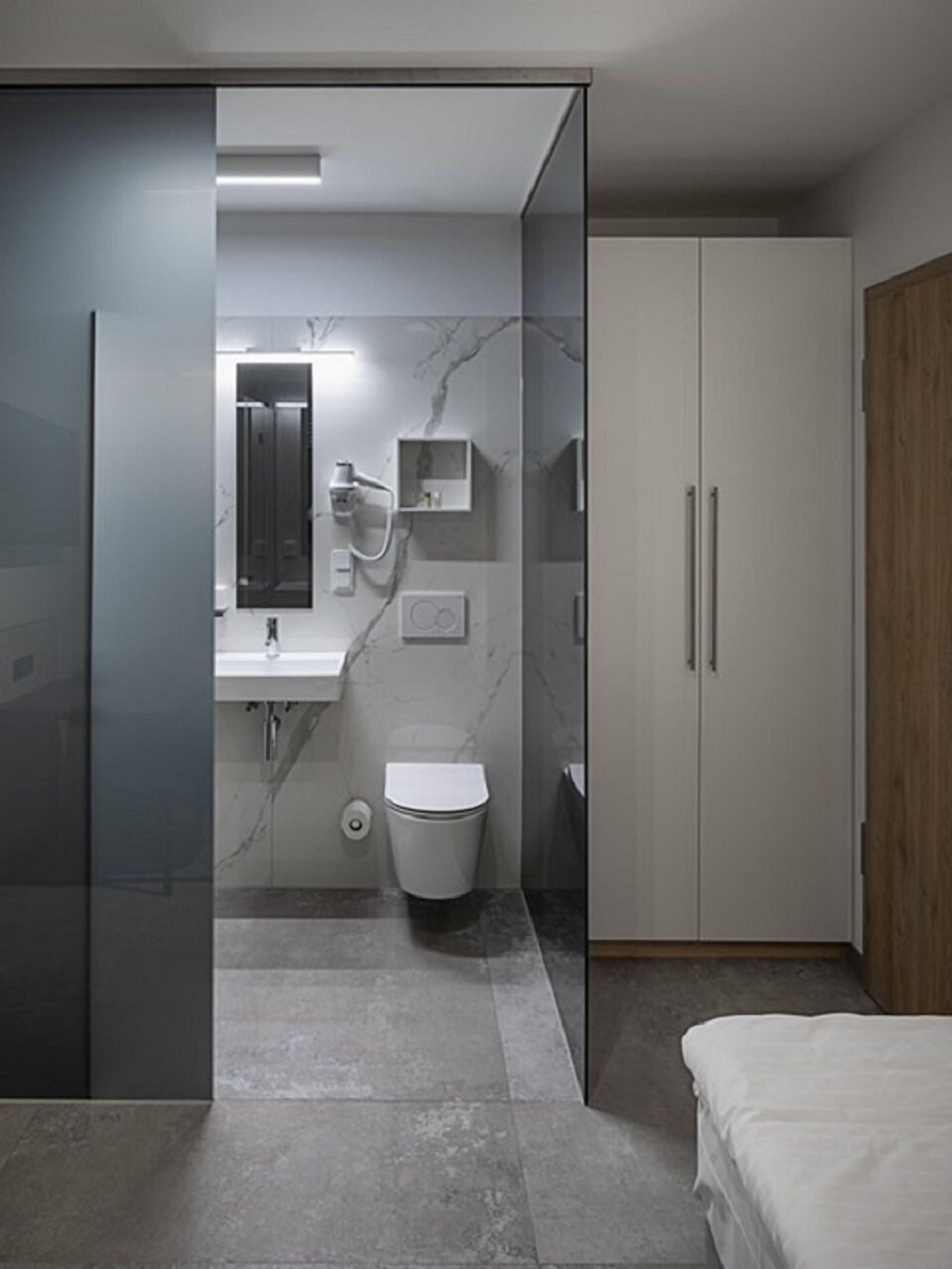 Un bagno moderno con box doccia in vetro, un water, un lavabo e un armadietto.
