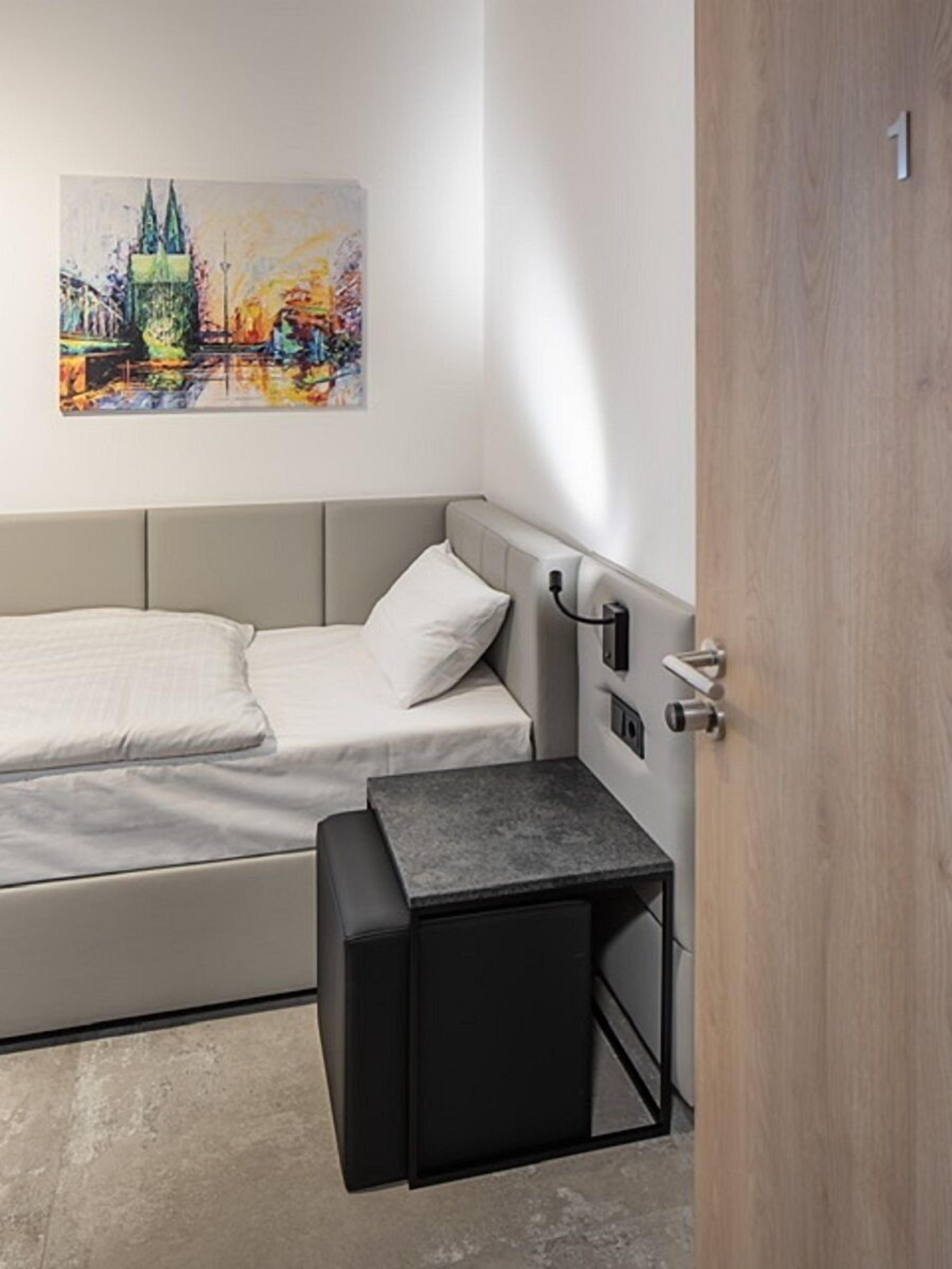 Un dormitorio moderno con cama, una mesita de noche y un cuadro en la pared.
