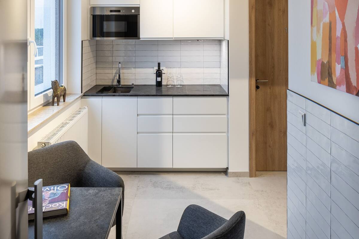 A modern kitchen with white cabinets, a black countertop, and a built-in oven.
