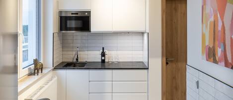 A modern kitchen with white cabinets, a black countertop, and a built-in oven.