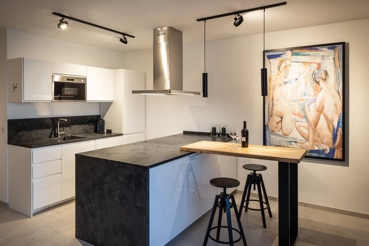 A modern kitchen with a large island, stainless steel appliances, and a contemporary painting on the wall.