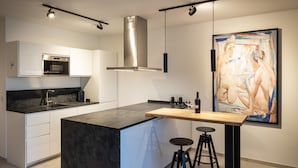 Une cuisine moderne dotée d’un grand îlot central, d’appareils électroménagers en acier inoxydable et d’un tableau contemporain accroché au mur.