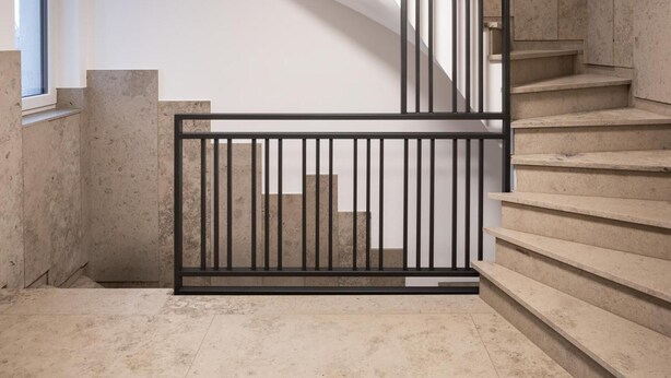 Un escalier moderne au design minimaliste, doté d’une rampe en métal noir et de marches en béton.