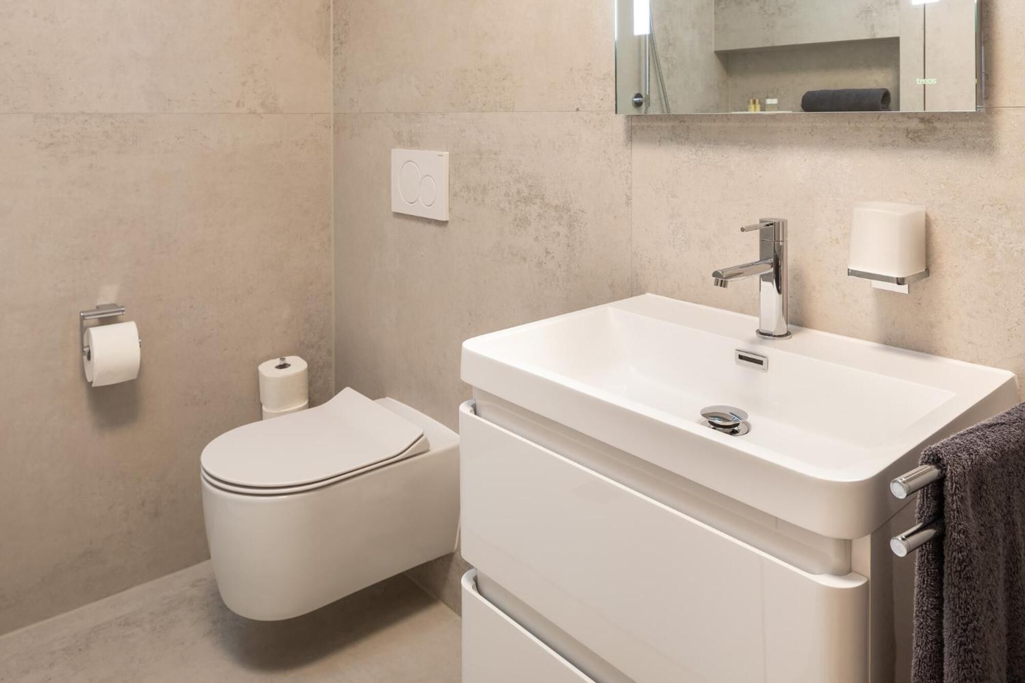 Une salle de bain moderne avec des toilettes, un lavabo et un miroir.