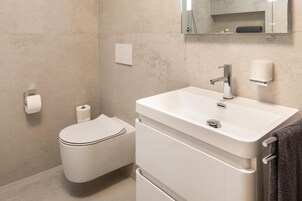 Un baño moderno con inodoro, lavamanos y espejo.