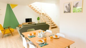 A modern living room with a dining area, a staircase, and a TV. - L'Eden - Duplex with Tertace (Combrit)