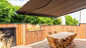 A wooden deck with a table and chairs, surrounded by a wooden fence and lush greenery. - L'Eden - Duplex with Tertace (Combrit)