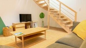 A modern living room with a wooden staircase, a television, a coffee table, and a sofa. - L'Eden - Duplex with Tertace (Combrit)