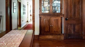 A wooden cabinet with glass doors, a red carpet, and a patterned rug in a hallway.