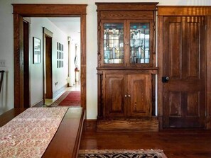 A wooden cabinet with glass doors, a red carpet, and a patterned rug in a hallway. - Wren Retweet- Country Estate in Center of C’Town (Chestertown)