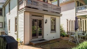 Ein zweistöckiges Haus mit Balkon, Eingangstür und einer Terrasse mit Sitzgelegenheiten.
