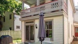 Eine überdachte Terrasse mit Tisch, Stühlen, einem Grill und einem Ziergeländer.