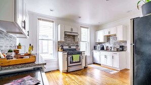 Une cuisine moderne avec des meubles blancs, un four en acier inoxydable et un réfrigérateur noir.