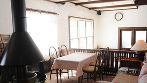A cozy living room with a fireplace, a dining table, and comfortable seating. - Petit Hotel Kanan (Chino)