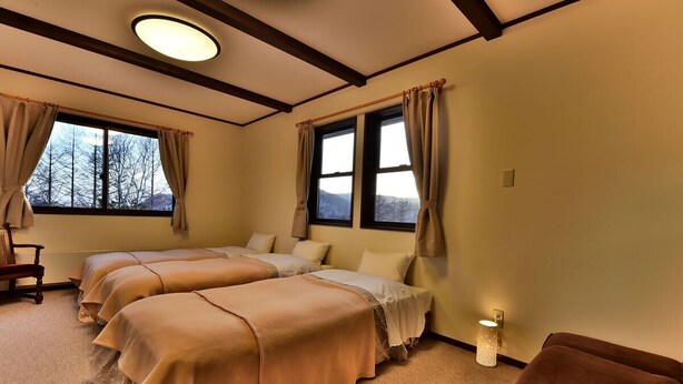 A room with three beds, a wooden chair, and a small table. - Petit Hotel Kanan (Chino)