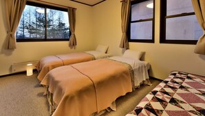 A room with two beds, a small table, and a window with curtains. - Petit Hotel Kanan (Chino)