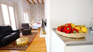 Una sala de estar con un sofá negro, un sillón gris y una alfombra estampada.
