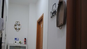 A narrow hallway with a white cabinet, a wooden door, and a wall-mounted mailbox. - Molo 5 (Naples)