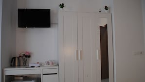 A bedroom with a bed, a desk with a coffee machine, a TV, and a wardrobe. - Molo 5 (Naples)