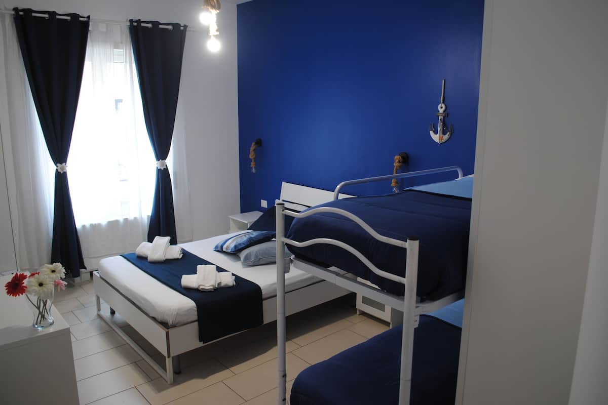 Una habitación de hotel con literas, una mesita de noche, una lámpara y una ventana con cortinas.