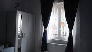 A room with a window, white wardrobe, and a small table with a plant. - Molo 5 (Naples)