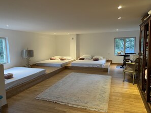 A modern bedroom with two beds, a large rug, and a vanity with a mirror.
