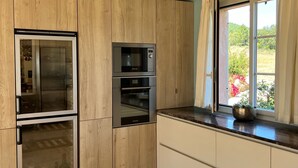 Een moderne keuken met houten kastjes, een inbouwoven, magnetron en koelkast.