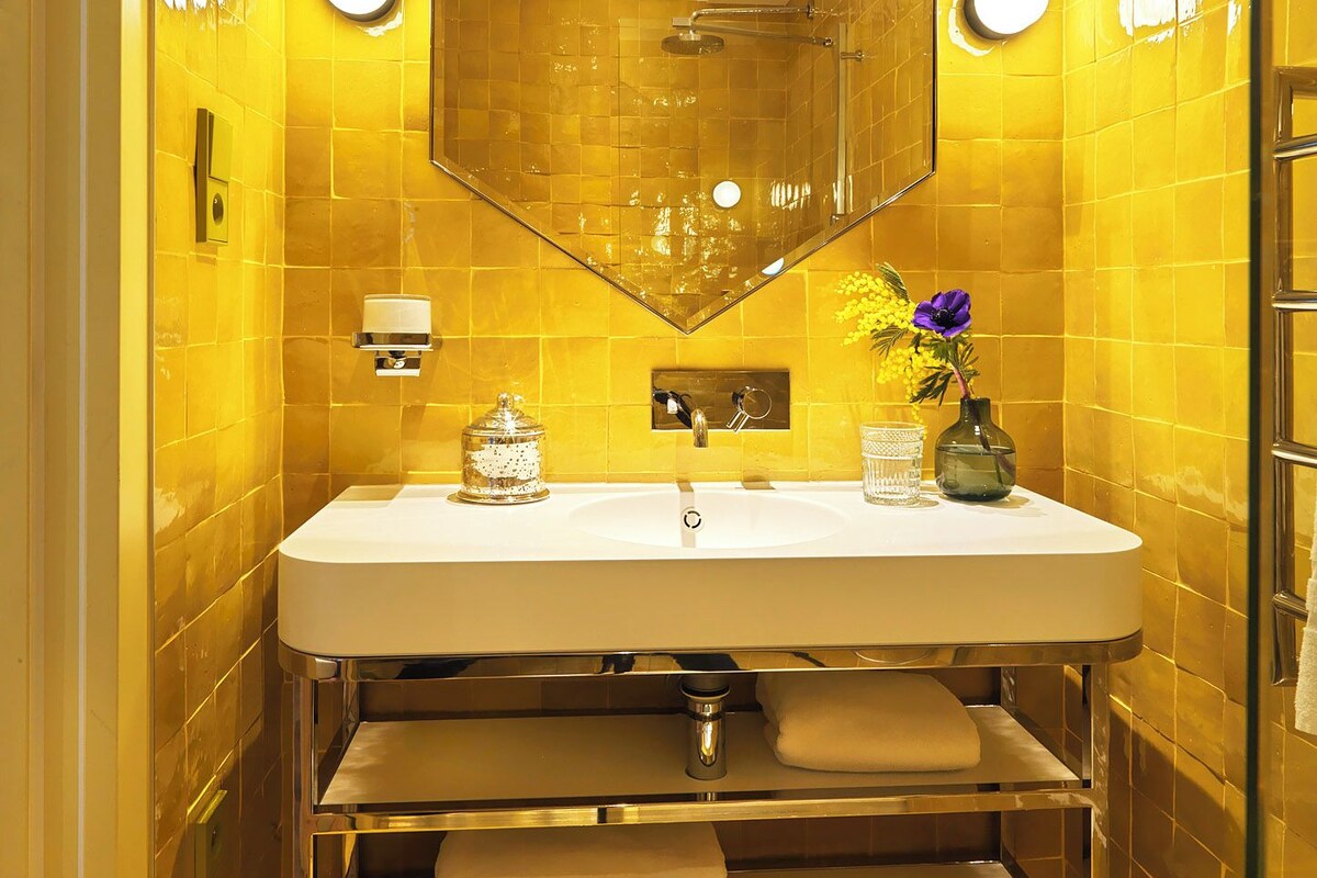 A bathroom with a large mirror, a sink, and a shower.