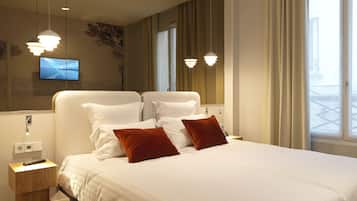 A modern hotel room with a large bed, a TV mounted on the wall, and a wooden nightstand.
