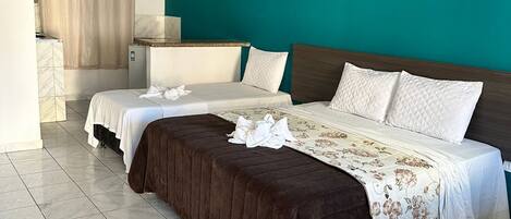 A hotel room with two beds, a bathroom, and a kitchenette.