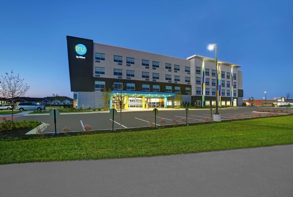 A modern hotel with a large sign, a parking lot, and a well-maintained lawn. - Tru by Hilton Stoughton (Stoughton)