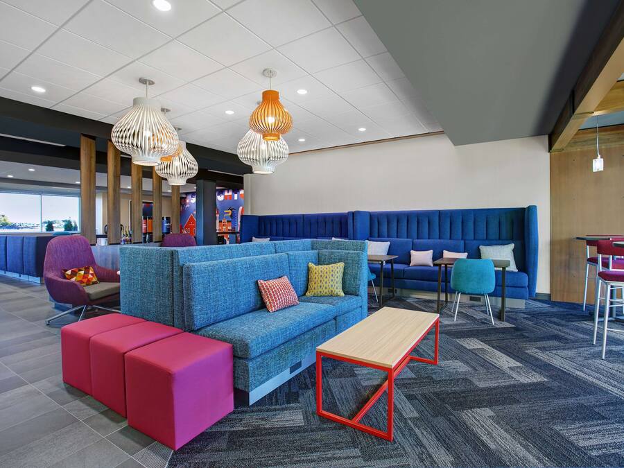 A modern lounge area with a blue sofa, red ottomans, and a wooden coffee table.