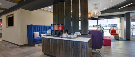 A modern reception area with a blue sofa, a wooden reception desk, and a large window offering a view of the city.