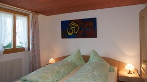 Un dormitorio con cama, dos lámparas de noche, una ventana con cortinas y una pared con un símbolo.