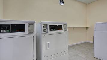 Una sala de lavandería con dos secadoras industriales y un armario blanco.