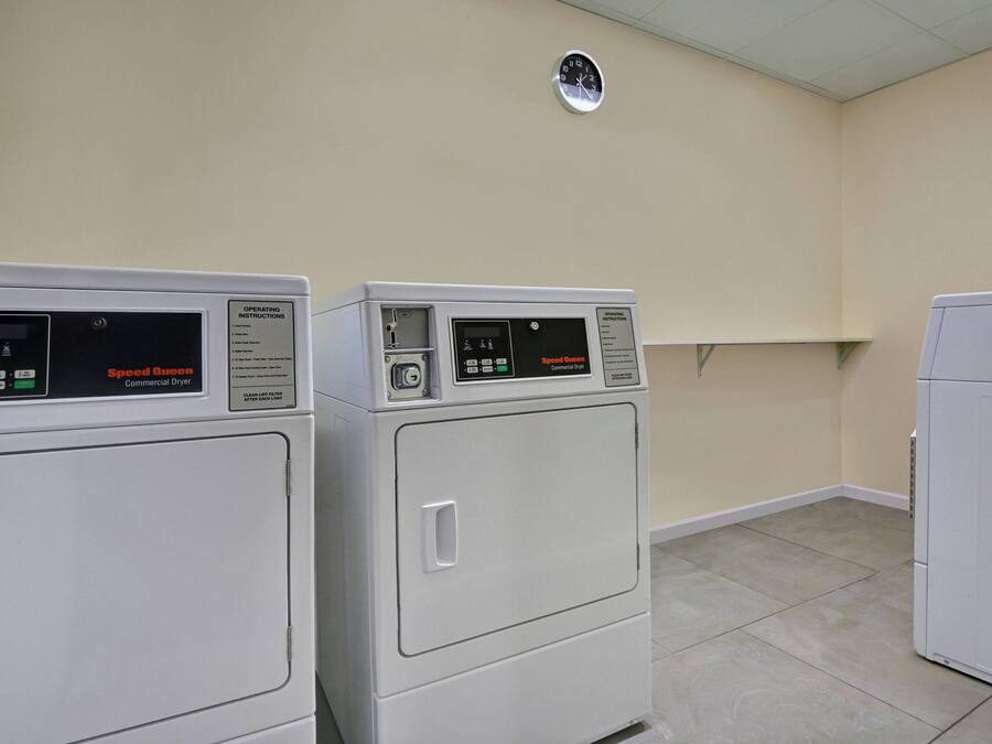 Una sala de lavandería con dos secadoras industriales y un armario blanco.