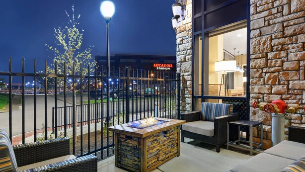 Een terras met rieten meubilair, een stenen openhaard en uitzicht op een stadion.