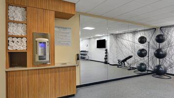 A reception area with a wooden counter, a self-service kiosk, and a wall-mounted TV.