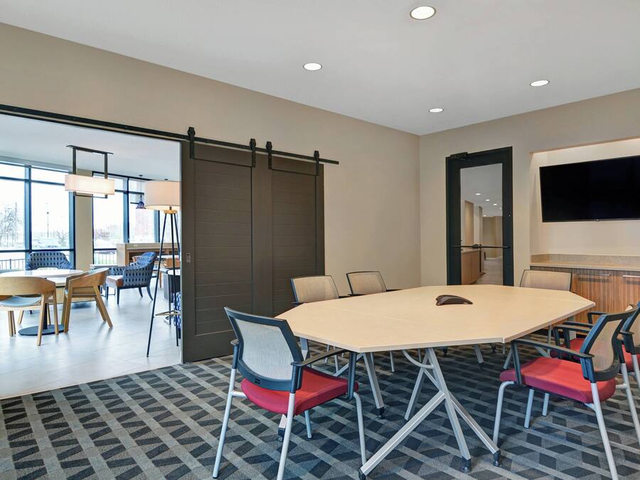 A conference room with a large table, six chairs, and a TV on the wall.