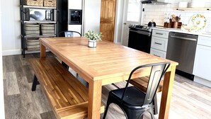 Ett modernt kök med ett matbord i trä, svarta stolar, en inbyggd ugn och en diskmaskin i rostfritt stål.