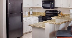 Enjoy cooking in this well-equipped kitchen with a refrigerator, microwave, stove, coffee maker, and knife block.