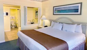Relax in a spacious room with a large bed, nightstand, and a beautiful framed painting above.