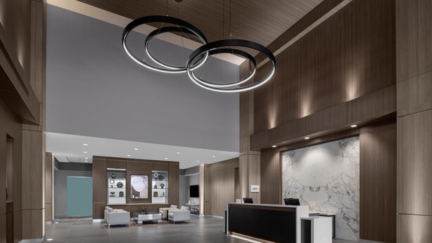 A modern lobby with a reception desk, seating area, and a large circular light fixture. - AC Hotel Pittsburgh Southpointe (Canonsburg)