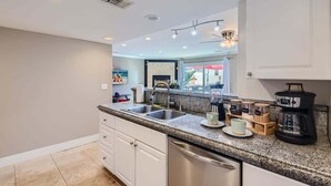 Una cocina moderna con encimeras de granito, electrodomésticos de acero inoxidable y un amplio ventanal con vistas al exterior.