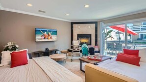 Habitación de hotel con cama, escritorio, silla, televisión, chimenea y vistas al exterior.