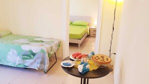 Een kleine kamer met een bed, een tafel met eten en een nachtkastje.