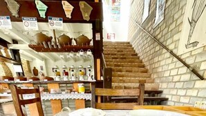 Una mesa con un plato de comida, una taza y una escalera al fondo.