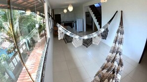 Un pasillo amplio con vistas a un jardín tropical, una escalera y una zona de cocina.