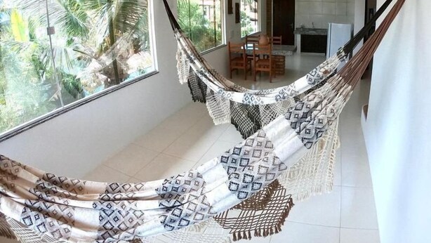 Una hamaca en una habitación luminosa con ventanas grandes, un comedor y una cocina.