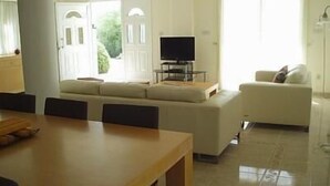 Un soggiorno moderno con un divano, una televisione e un'area pranzo con un tavolo.